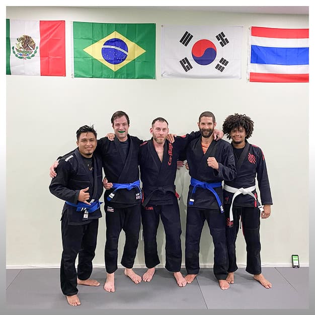 Group of martial artists in Brazilian Jiu-Jitsu uniforms at NYC dojo.