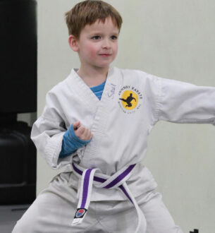 Young boy practicing karate in uniform at after school program.