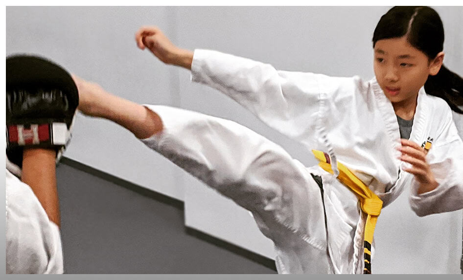 Young girl performing a high kick during martial arts class at Johnny Karate NYC.