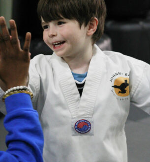 Young boy in karate uniform smiling during a birthday party event.