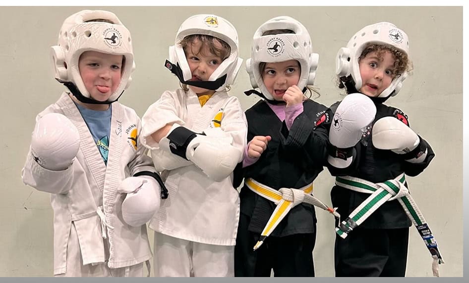 Kids practicing martial arts in protective gear at preschool class.