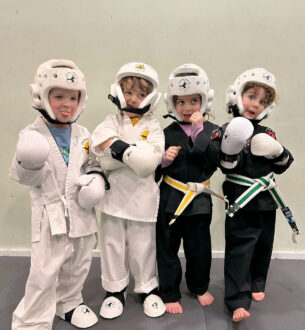 Group of young children in karate uniforms and protective gear at Johnny Karate NYC.