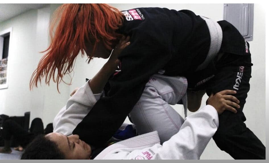 Young woman practicing Brazilian Jiu-Jitsu techniques on her partner.