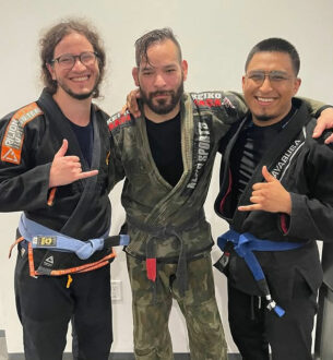 Group of three men in BJJ gis at Johnny Karate NYC, smiling and posing after training.