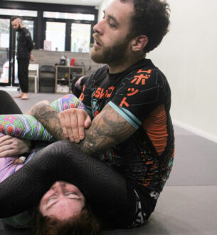 Male BJJ practitioner demonstrating ground technique at Johnny Karate NYC.