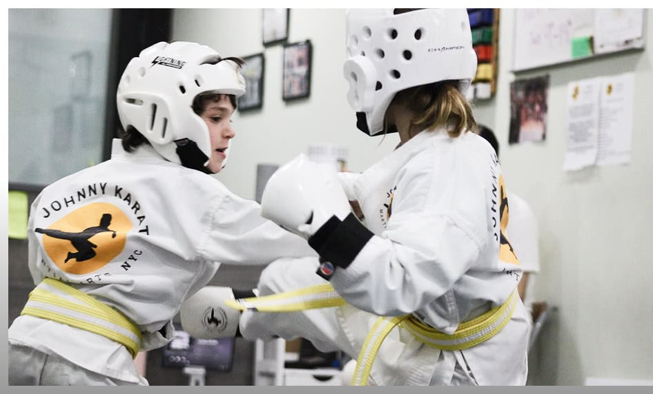 Young students practicing martial arts with protective gear at Johnny Karate NYC.