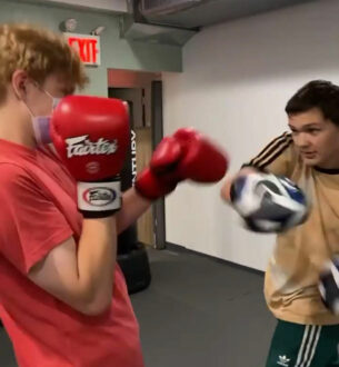 Two young men practicing kickboxing with gloves in a gym at Johnny Karate NYC.