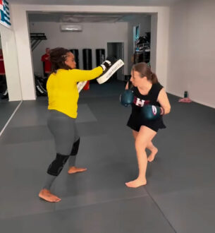 Female student practicing kickboxing with instructor at Johnny Karate NYC gym.