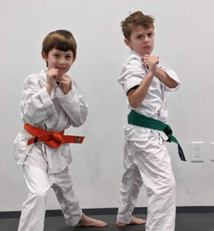 Young boys practicing martial arts in karate uniforms with colored belts.