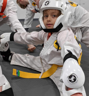 Young boy practicing martial arts in protective gear at Johnny Karate NYC.
