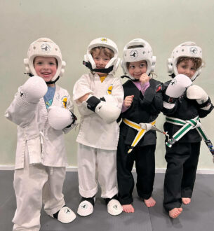 Kids in karate uniforms and helmets at preschool martial arts class.