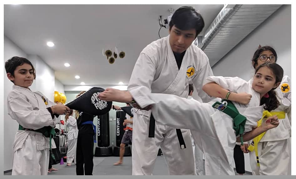 Kids martial arts class practicing kicks at Johnny Karate NYC in a modern dojo.