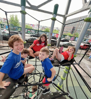 Kids climbing on a playground structure at Johnny Karate NYC summer camp. Fun outdoor activity for c.