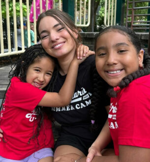 Smiling camp counselor with two happy kids at summer camp, outdoor setting.