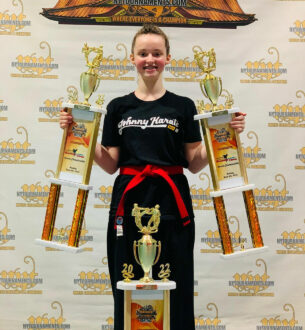 Teen martial artist holding two trophies at Johnny Karate NYC event.