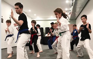 Kids practicing karate in class at Johnny Karate NYC, focusing on discipline and skill.