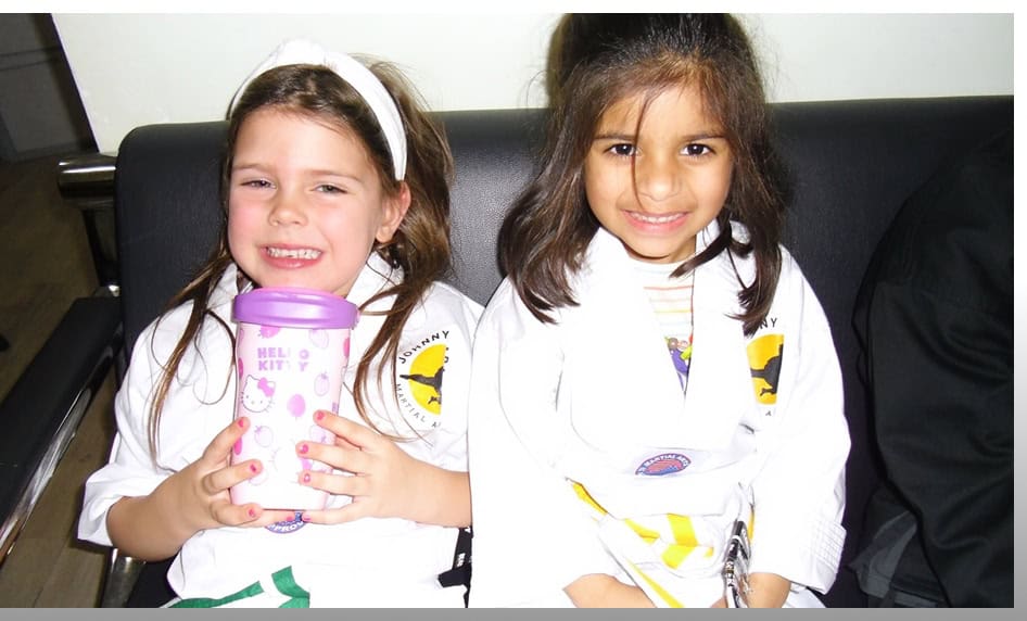 Two smiling girls in karate uniforms at Johnny Karate NYC birthday party.